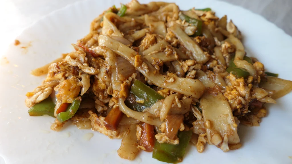 Chinese Style Stir fried noodles served on a white plate. Made at home with eggs and Veg.
